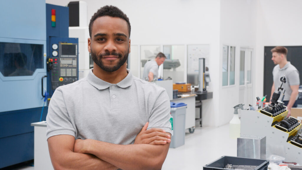 Portrait Of Male Engineer On Factory Floor Of Busy Workshop